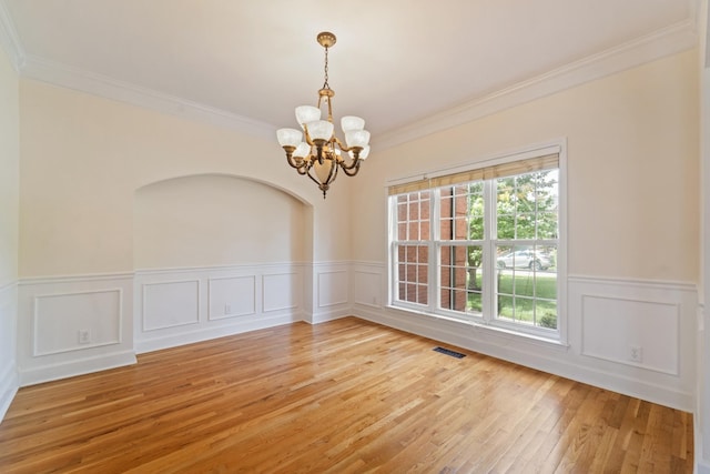 spare room with light wood-style floors, visible vents, a notable chandelier, and crown molding