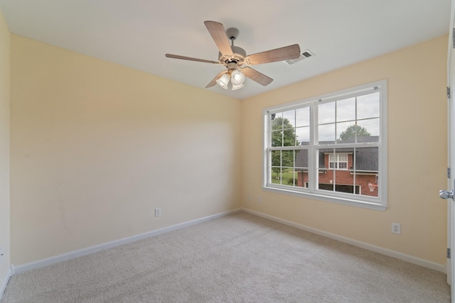 spare room with light carpet, ceiling fan, visible vents, and baseboards