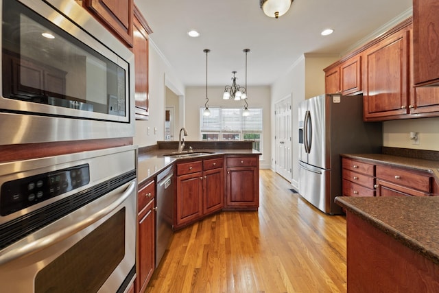 kitchen with pendant lighting, crown molding, dark countertops, appliances with stainless steel finishes, and a sink