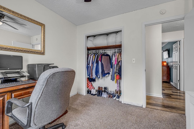 office area featuring ceiling fan, dark colored carpet, a textured ceiling, and baseboards