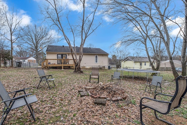 view of yard featuring a trampoline, fence, and a deck