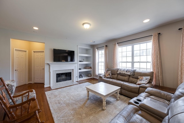 living area with built in features, recessed lighting, a premium fireplace, light wood-type flooring, and baseboards