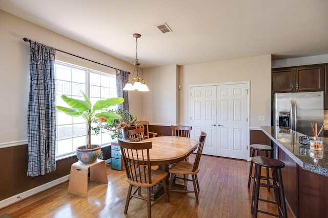 dining space with visible vents, dark wood-style flooring, a wealth of natural light, and an inviting chandelier