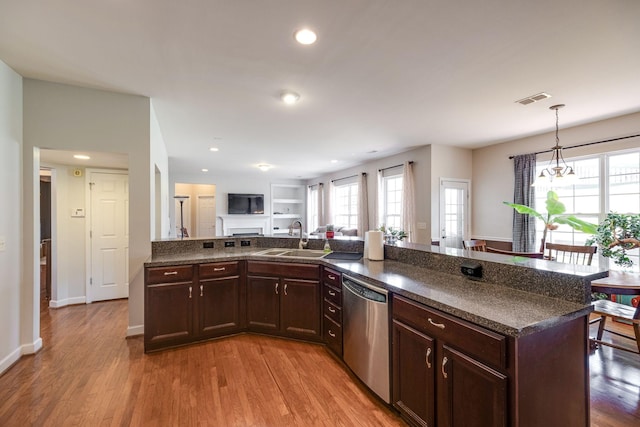 kitchen with decorative light fixtures, visible vents, stainless steel dishwasher, open floor plan, and a sink