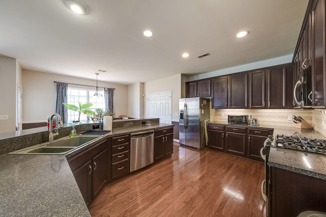 kitchen featuring dark wood-style flooring, decorative light fixtures, visible vents, appliances with stainless steel finishes, and a sink