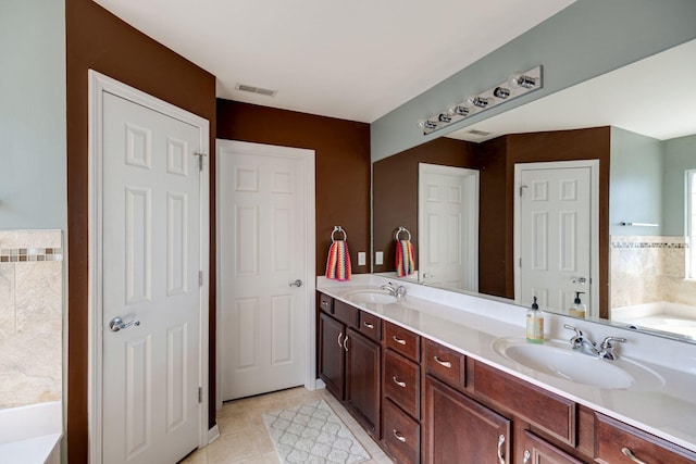 bathroom featuring visible vents, double vanity, a sink, and a bathing tub