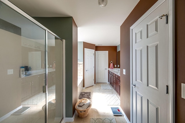 bathroom with a stall shower, vanity, and baseboards