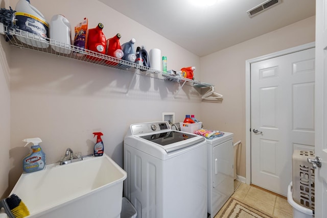 clothes washing area featuring laundry area, light tile patterned floors, visible vents, washing machine and dryer, and a sink