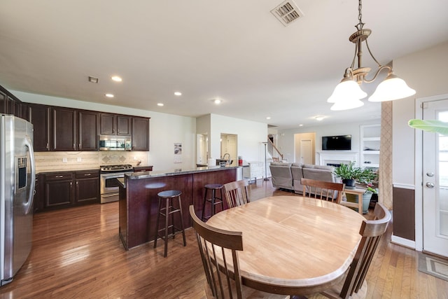 dining space featuring a fireplace, visible vents, wood finished floors, and recessed lighting