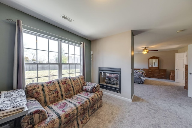 living room featuring light carpet, baseboards, visible vents, and a glass covered fireplace