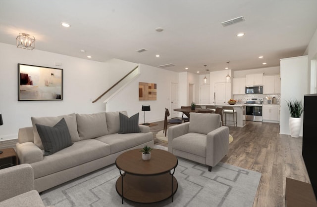 living room with baseboards, visible vents, wood finished floors, and recessed lighting