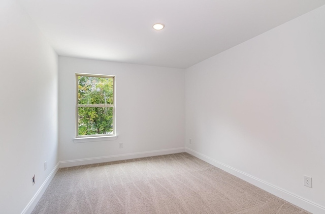 empty room featuring recessed lighting, light carpet, and baseboards