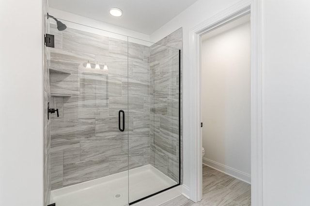 full bath featuring baseboards, a shower stall, and toilet