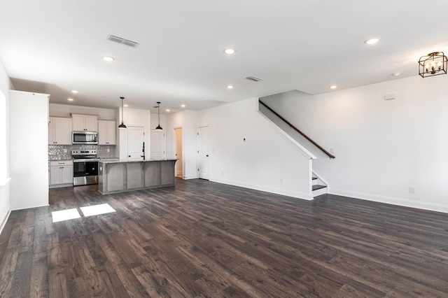 unfurnished living room with baseboards, visible vents, dark wood-type flooring, stairs, and recessed lighting