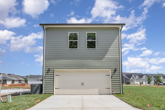 view of side of home with a garage, concrete driveway, a lawn, and a residential view