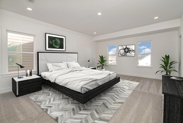 carpeted bedroom featuring recessed lighting, a decorative wall, and baseboards