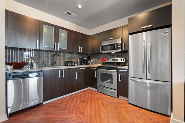 kitchen with stainless steel appliances, visible vents, backsplash, and dark brown cabinets