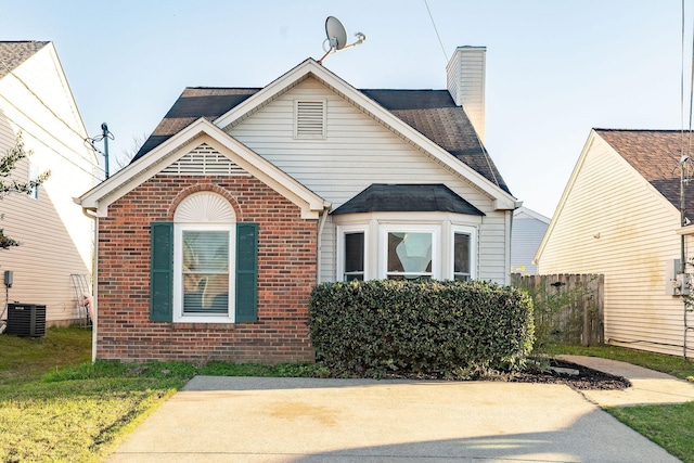 view of front of home with central air condition unit, a chimney, fence, and brick siding