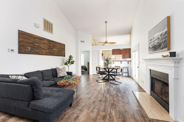 living area with high vaulted ceiling, a fireplace with flush hearth, visible vents, and dark wood-style flooring