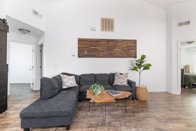 living area featuring a barn door, a high ceiling, and visible vents