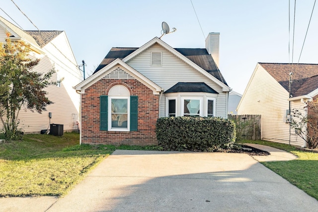 bungalow with a front yard, a chimney, and brick siding