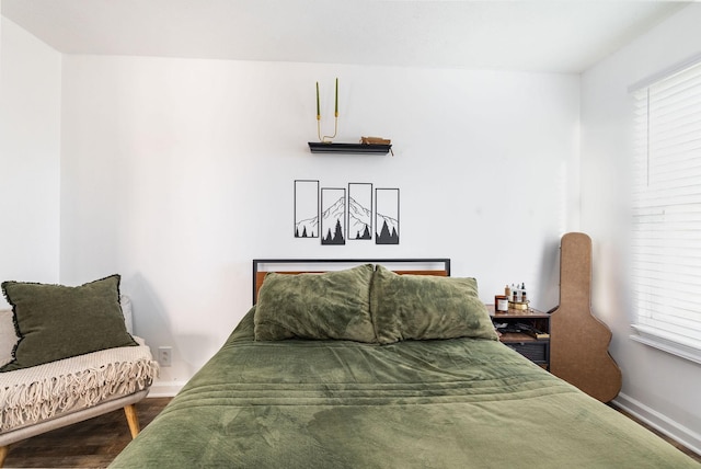 bedroom featuring multiple windows, baseboards, and wood finished floors