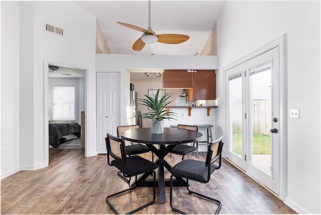 dining room with high vaulted ceiling, a wealth of natural light, light wood-type flooring, and visible vents