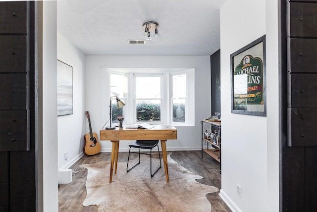 office area with visible vents, baseboards, and wood finished floors