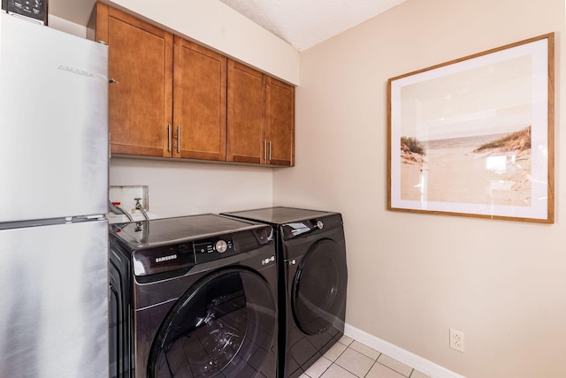 washroom with light tile patterned floors, baseboards, cabinet space, and washer and dryer