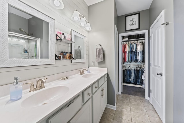 full bath featuring double vanity, tile patterned flooring, a sink, and a shower stall