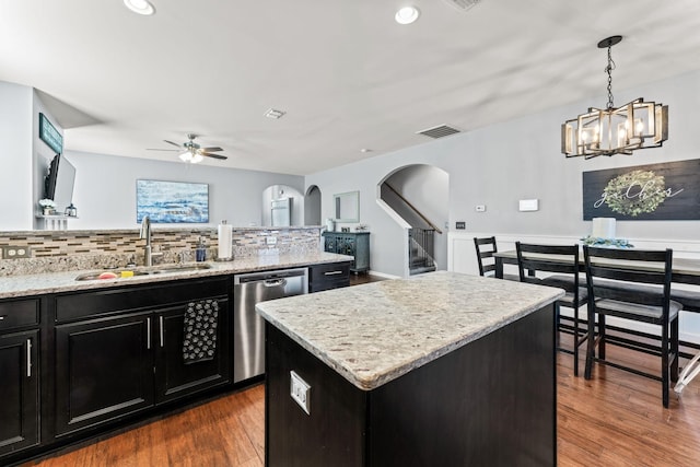 kitchen with dishwasher, a kitchen island, dark wood-style flooring, dark cabinetry, and a sink