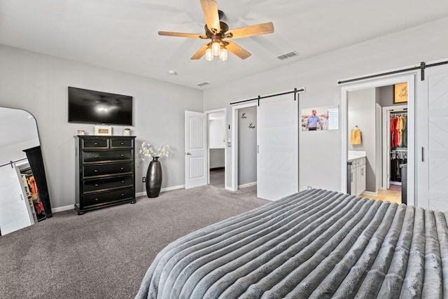 bedroom featuring a barn door, carpet flooring, visible vents, baseboards, and a spacious closet