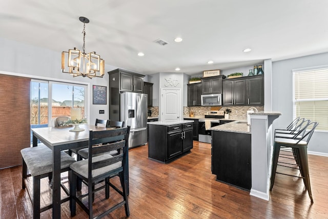 kitchen featuring dark wood-style floors, visible vents, appliances with stainless steel finishes, and a center island