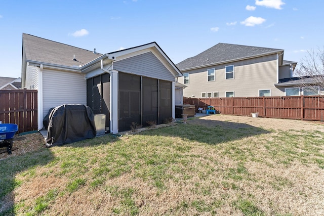 rear view of house with a sunroom, a fenced backyard, and a yard