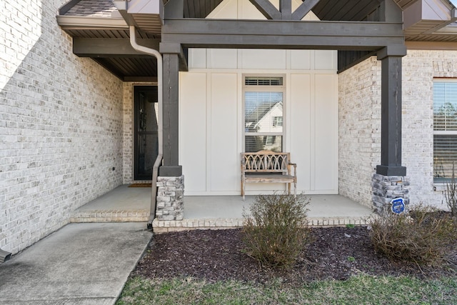 entrance to property with covered porch and brick siding