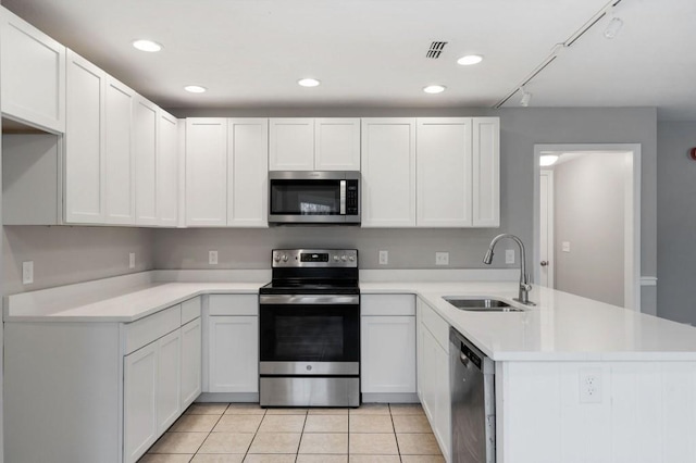 kitchen with stainless steel appliances, a sink, light countertops, and white cabinetry