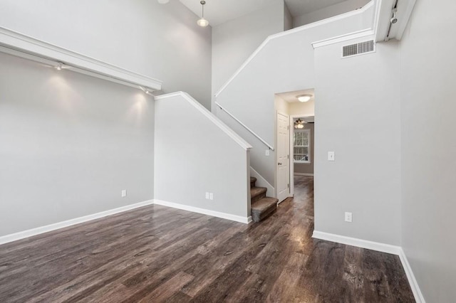 interior space with visible vents, dark wood finished floors, baseboards, ceiling fan, and stairway