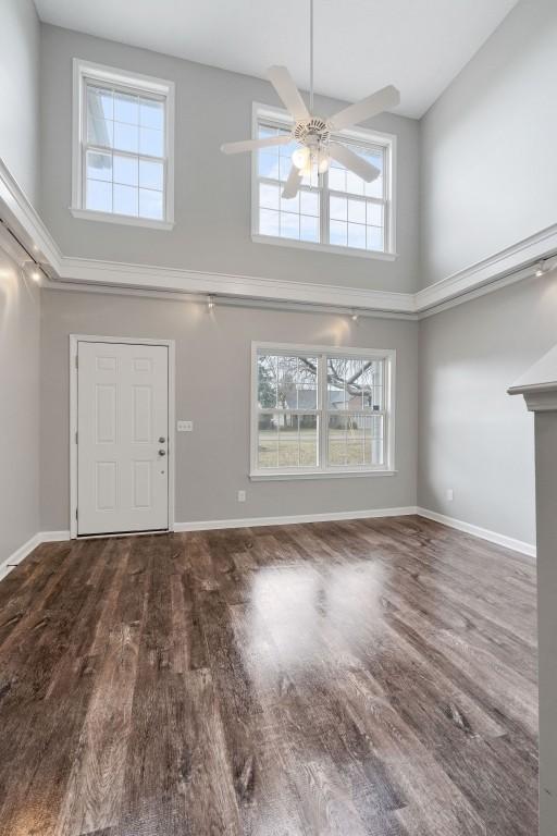 foyer entrance with ceiling fan, a high ceiling, baseboards, and wood finished floors