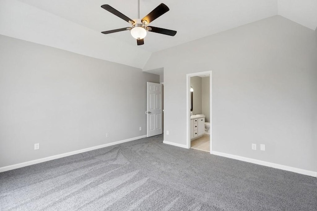 unfurnished bedroom with vaulted ceiling, connected bathroom, light colored carpet, and baseboards