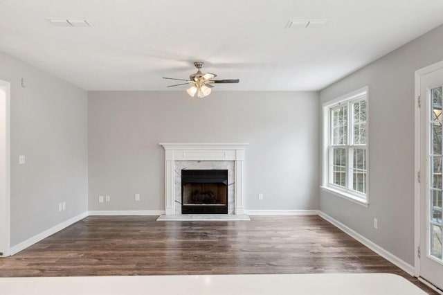 unfurnished living room featuring baseboards, a fireplace, a ceiling fan, and dark wood-style flooring