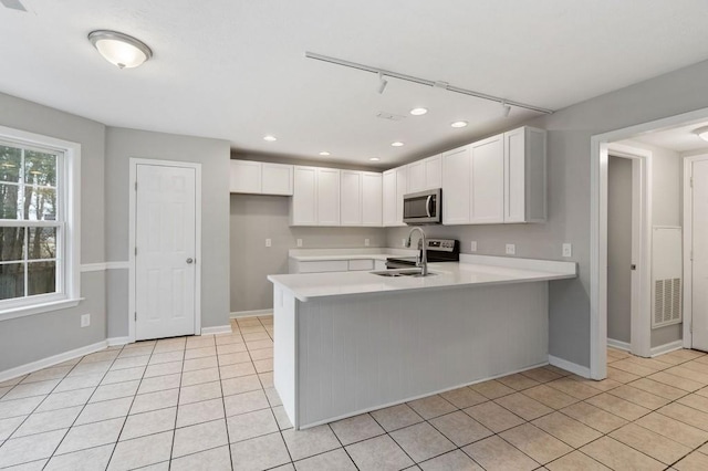 kitchen featuring visible vents, stainless steel microwave, a peninsula, light countertops, and white cabinetry