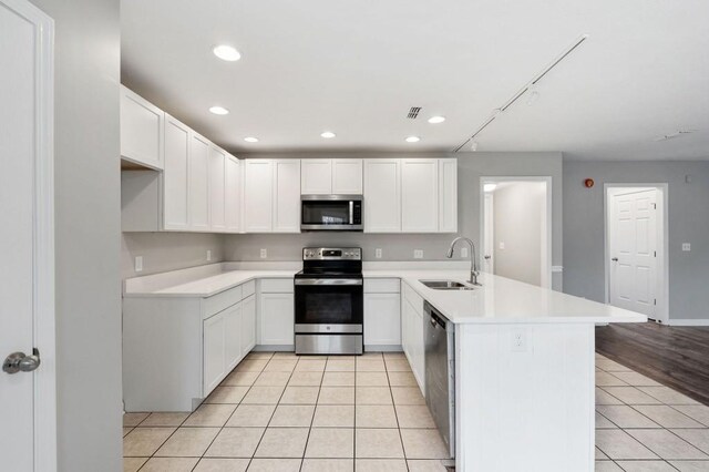 kitchen featuring stainless steel appliances, white cabinets, light countertops, and a sink