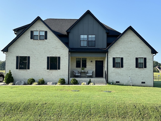 view of front of property with board and batten siding, crawl space, brick siding, and a front lawn