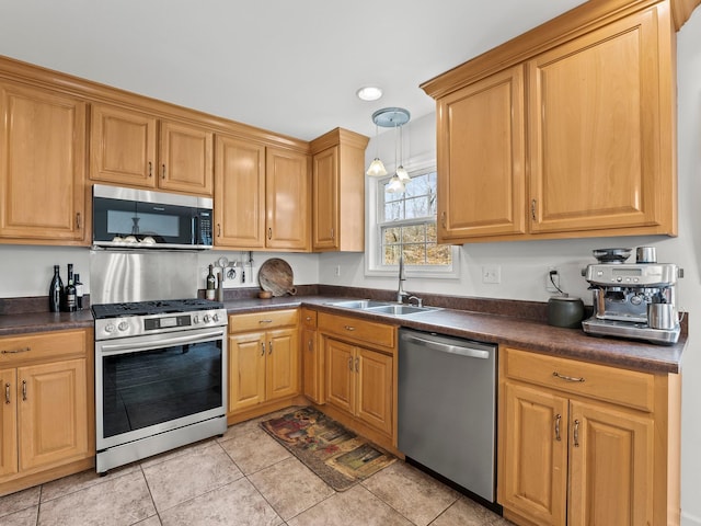 kitchen with stainless steel appliances, dark countertops, hanging light fixtures, light tile patterned flooring, and a sink