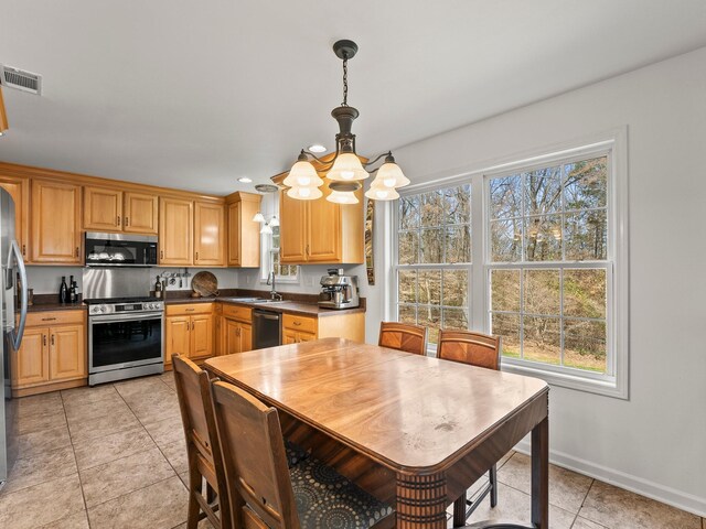 kitchen with light tile patterned floors, visible vents, appliances with stainless steel finishes, a wealth of natural light, and dark countertops