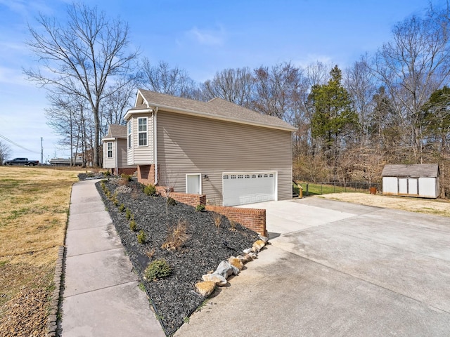 view of home's exterior with an outbuilding, a shingled roof, concrete driveway, fence, and a shed