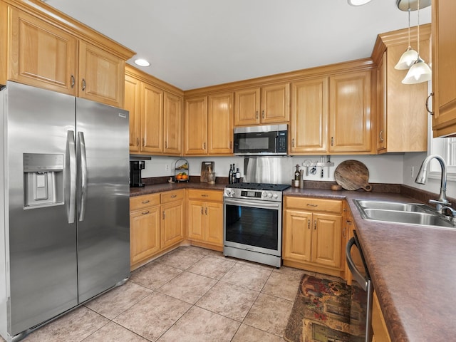 kitchen featuring appliances with stainless steel finishes, dark countertops, a sink, and light tile patterned flooring