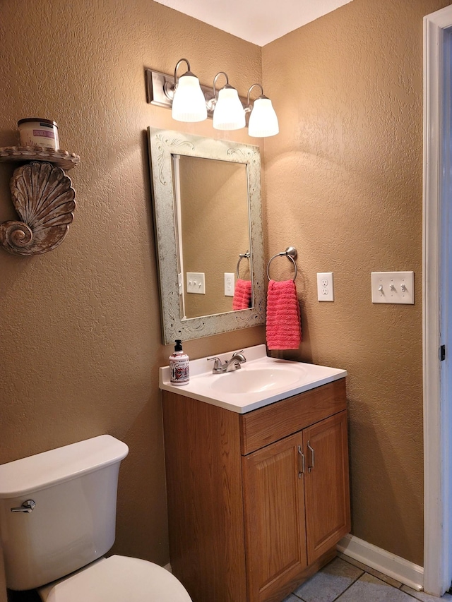 bathroom featuring a textured wall, vanity, toilet, and tile patterned floors