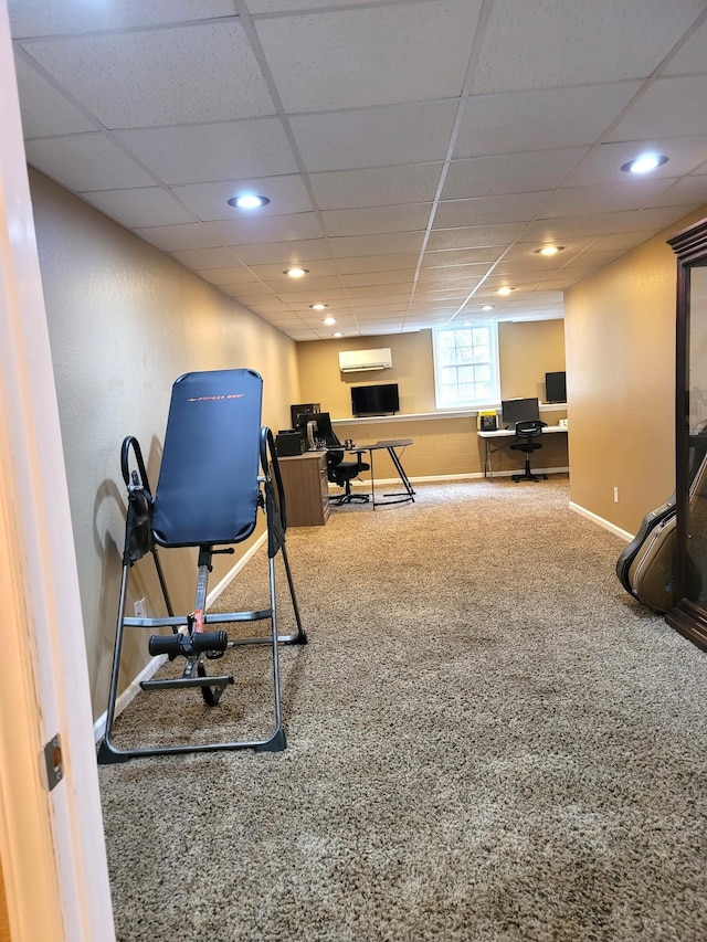 exercise room with a drop ceiling, recessed lighting, carpet floors, baseboards, and a wall mounted air conditioner