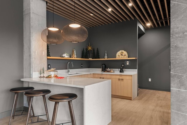 bar featuring light wood-style flooring, a sink, and decorative light fixtures